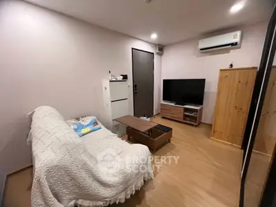 Cozy living room with modern decor, featuring a comfortable sofa, sleek TV stand, and efficient air conditioning.