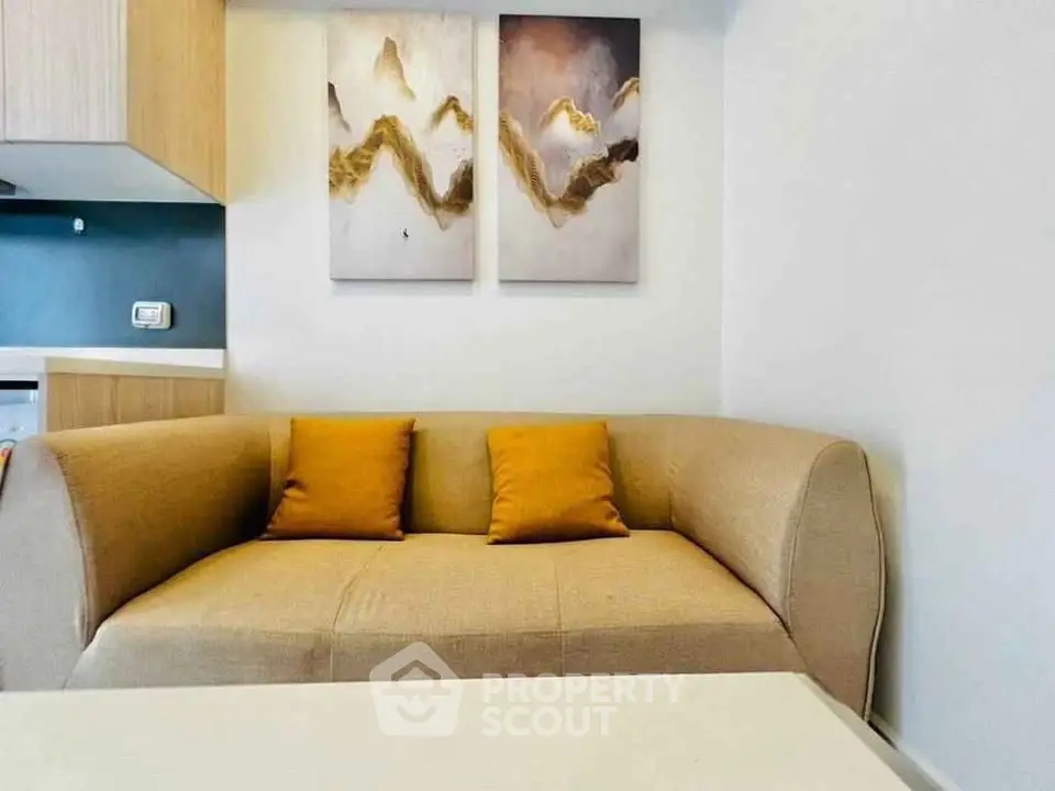 Modern living room with stylish beige sofa and abstract art on the wall, perfect for cozy relaxation.