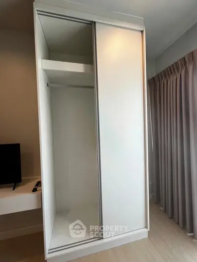 Spacious white wardrobe in modern bedroom with natural light and elegant curtains.