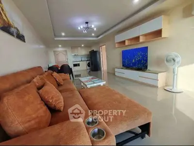 Spacious living room with modern decor and large TV, perfect for relaxation.