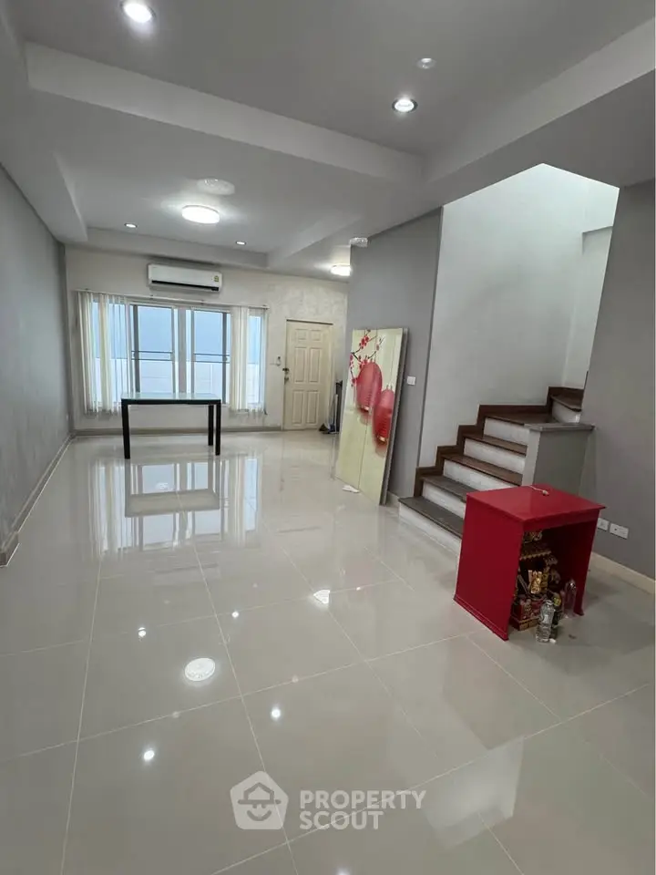 Spacious modern living room with sleek tile flooring and staircase, perfect for stylish urban living.