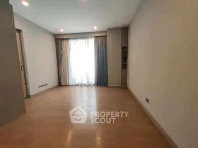 Spacious empty room with wooden flooring and large window, ideal for customization.