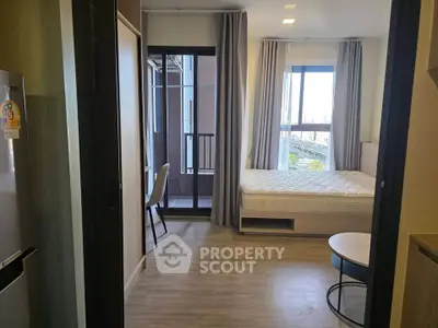 Modern studio apartment with balcony and natural light, featuring a cozy bed and stylish decor.