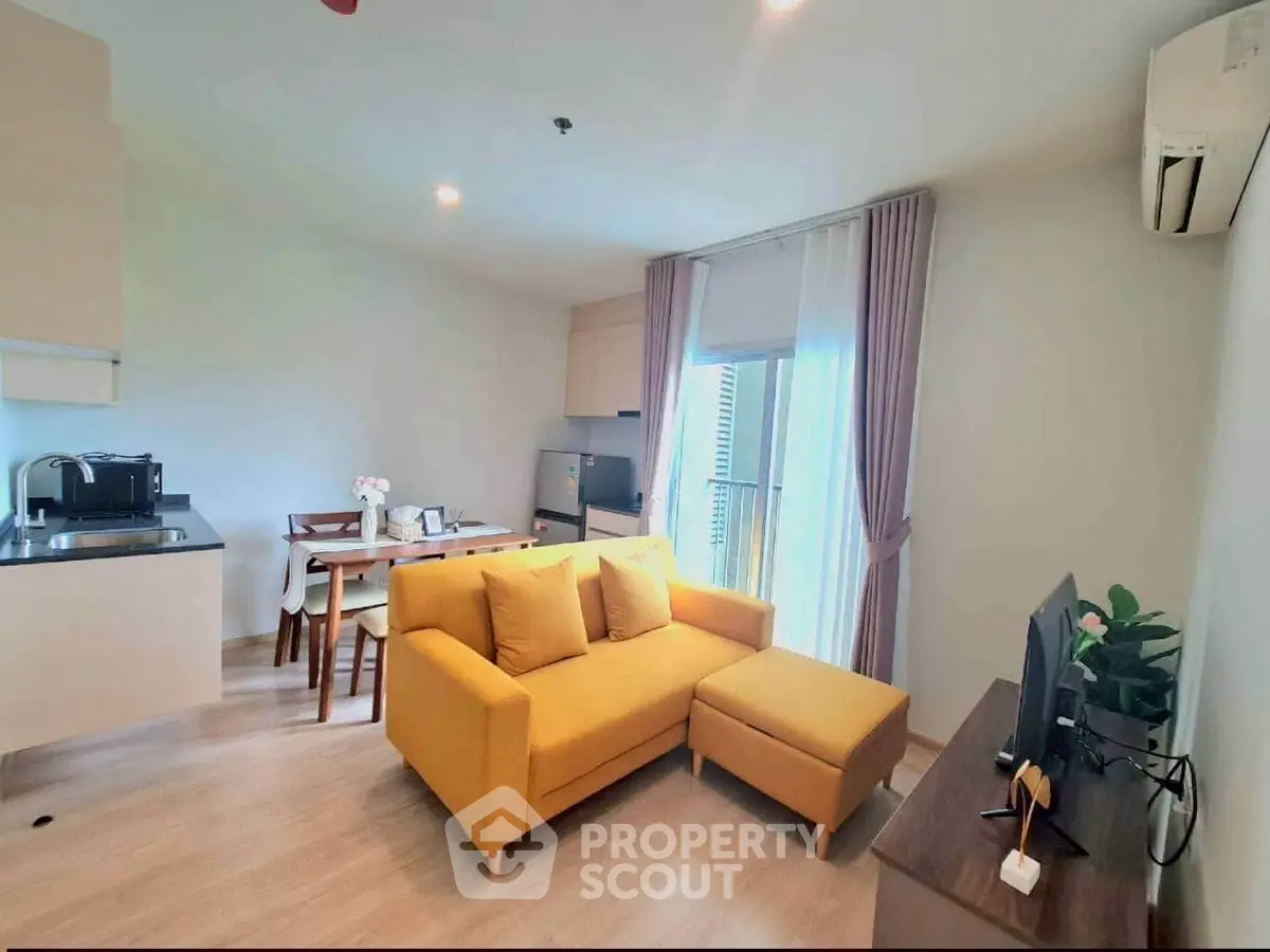 Modern living room with yellow sofa, open kitchen, and dining area in bright apartment.