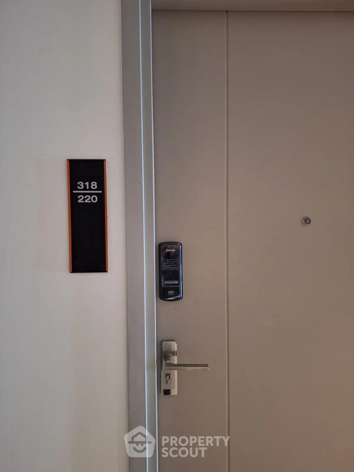 Modern apartment door with electronic lock and room number signage.