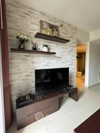 Modern living room with stylish TV setup and elegant decor on brick accent wall.
