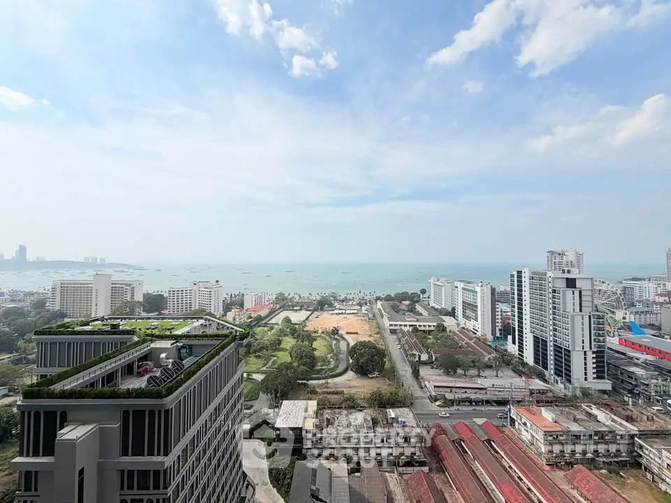 Stunning high-rise view of cityscape and ocean, showcasing modern architecture and lush greenery.