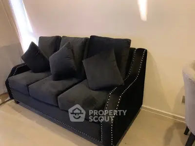 Elegant black velvet sofa with studded accents in a cozy living room setting.