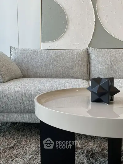 Modern living room with stylish gray sofa and geometric decor on round table.