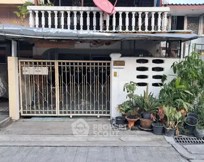 Charming urban residence with gated entrance and lush potted plants, offering a cozy and secure living environment.