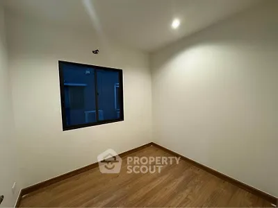 Spacious empty room with wooden flooring and a large window, perfect for customization.