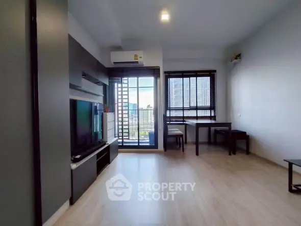 Modern living room with balcony and city view, featuring sleek furniture and natural light.