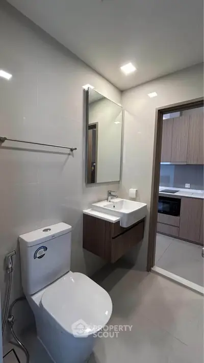 Modern bathroom with sleek fixtures and adjacent kitchen view