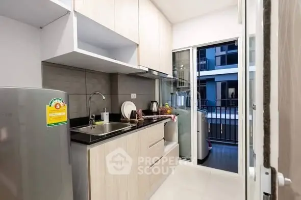 Modern kitchen with sleek cabinetry and balcony access in a stylish apartment.