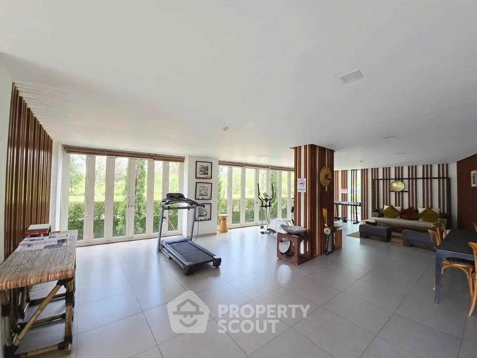 Spacious fitness area with modern equipment and large windows offering garden views.