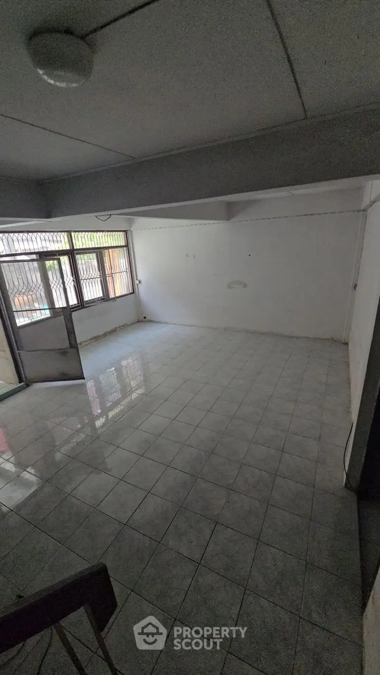 Spacious empty room with tiled flooring and large windows for natural light.