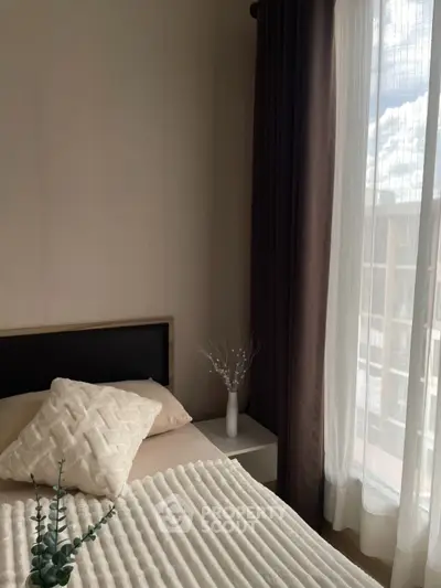 Cozy bedroom with elegant decor and large window offering natural light and city view.