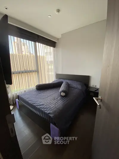 Cozy bedroom with modern decor and large window offering natural light.