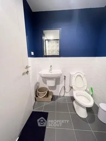 Modern bathroom with blue and white tiles, featuring a sleek sink and toilet.