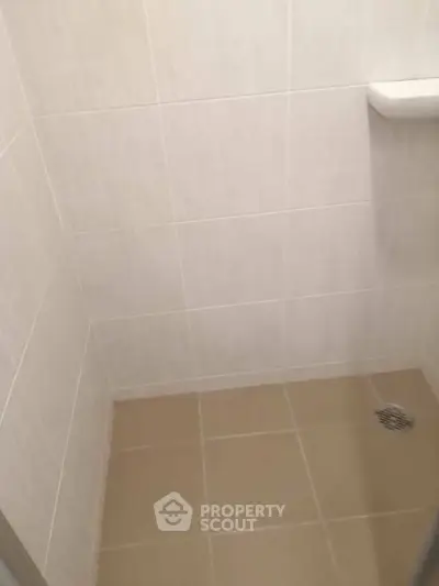 Minimalist bathroom shower area with tiled walls and floor