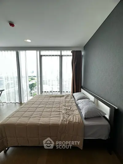 Spacious bedroom with large windows offering stunning city views