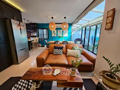 Stylish modern living room with leather sofa, open kitchen, and large windows for natural light.