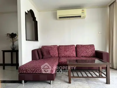 Spacious living room with elegant maroon sofa and modern air conditioning unit.