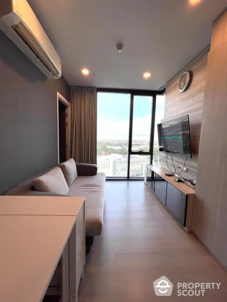 Modern living room with large window and city view, featuring sleek furniture and wall-mounted TV.