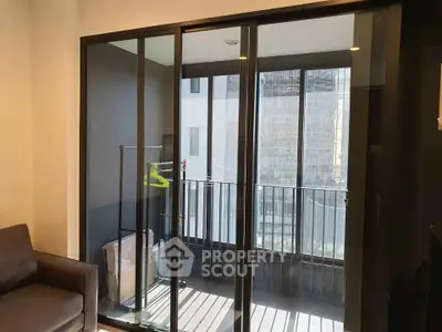 Modern apartment with sliding glass doors leading to a cozy balcony with city views.