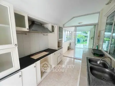 Spacious kitchen with open layout and garden view, featuring modern cabinetry and dual sinks.