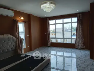 Spacious bedroom with large windows and elegant chandelier in modern home.