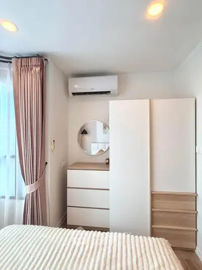 Modern bedroom with stylish furniture and air conditioning, featuring elegant curtains and a cozy ambiance.
