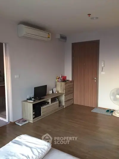 Cozy living room with wooden flooring and modern air conditioning unit.