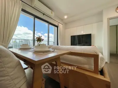 Modern living room with large windows and city view, featuring cozy furniture and elegant decor.