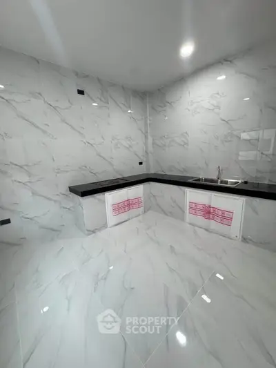 Sleek modern kitchen with marble tiles and black countertops, perfect for culinary enthusiasts.