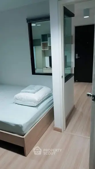 Modern bedroom with minimalist design and wooden flooring, featuring a cozy bed and stylish decor.