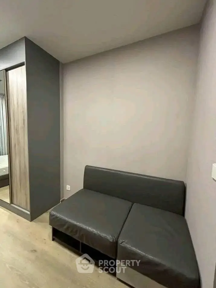 Modern minimalist living room with sleek gray sofa and wooden flooring.