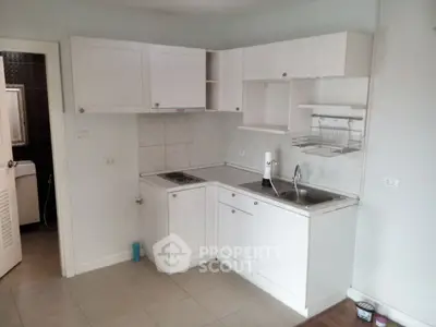 Compact kitchen with white cabinets and stainless steel sink in modern apartment