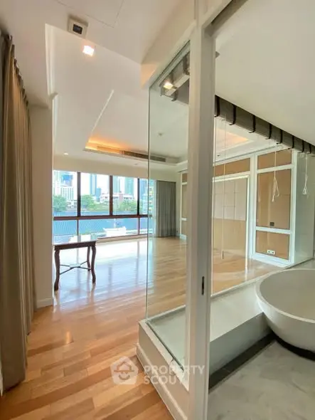 Spacious modern apartment with hardwood floors and large windows offering city views.