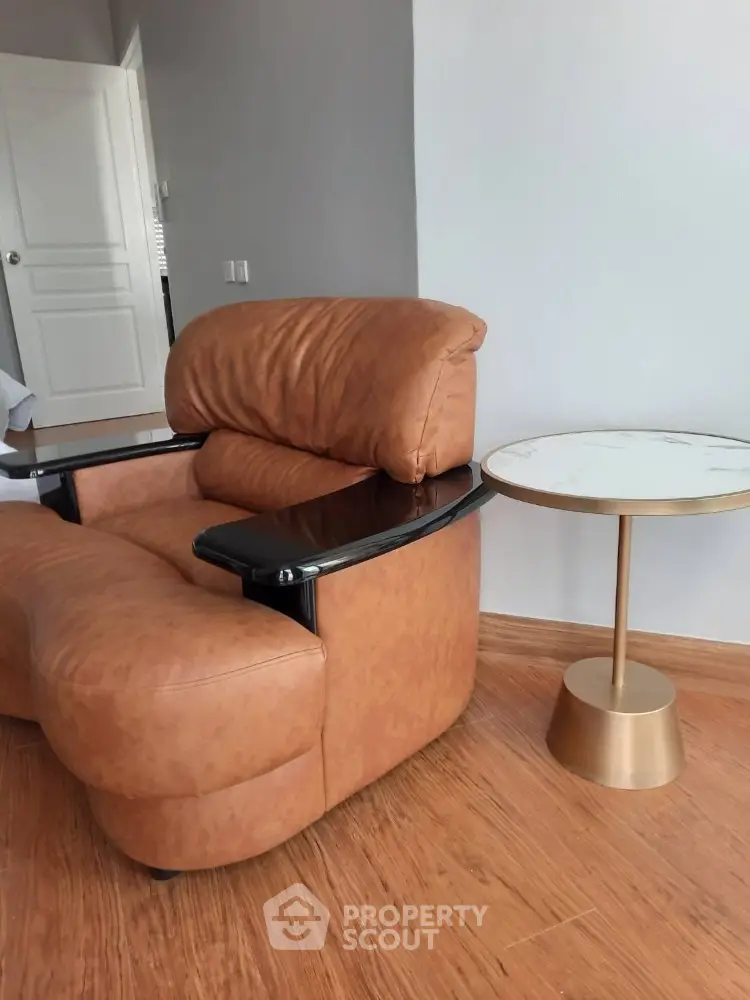 Cozy living room corner with stylish leather armchair and elegant side table on wooden flooring.