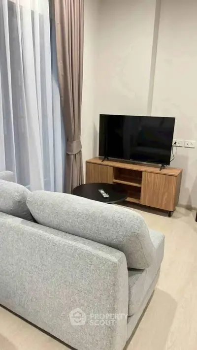 Modern living room with cozy gray sofa and sleek TV setup, perfect for relaxation.