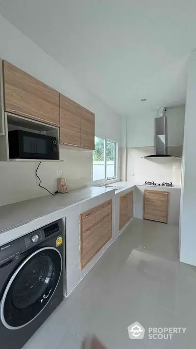 Modern kitchen with sleek design, featuring built-in microwave, washing machine, and gas stove.