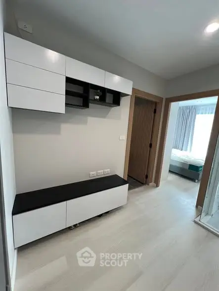 Modern apartment hallway with sleek storage and view into a cozy bedroom