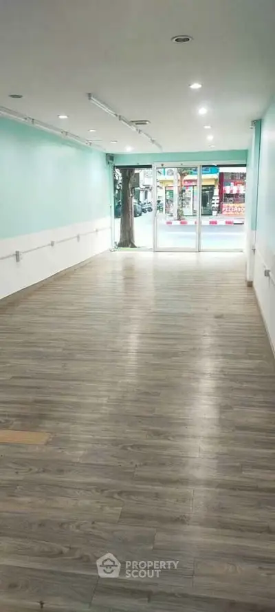 Spacious commercial space with large windows and wood flooring, ideal for retail or office use.