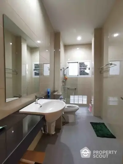 Spacious and modern bathroom with large mirror, well-lit with natural light, featuring a full-sized bathtub and ample counter space.