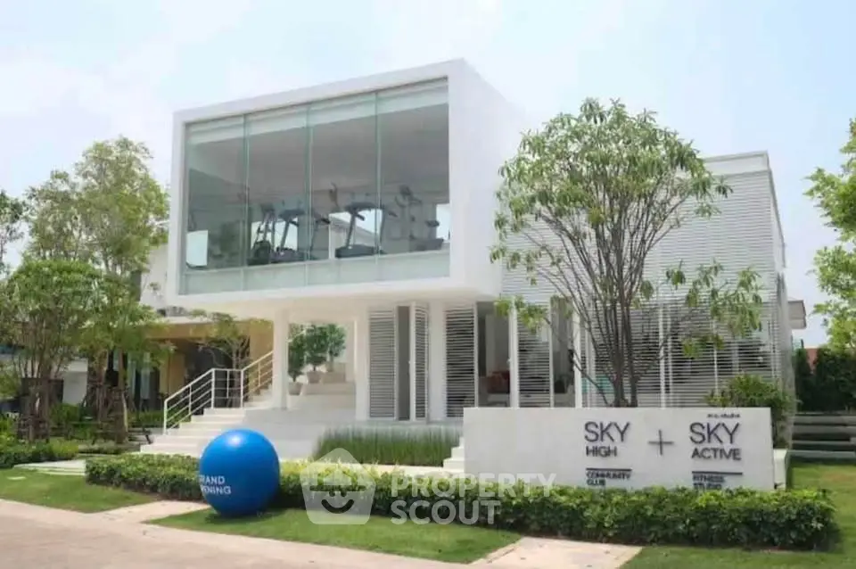 Modern two-story building with glass facade and lush landscaping