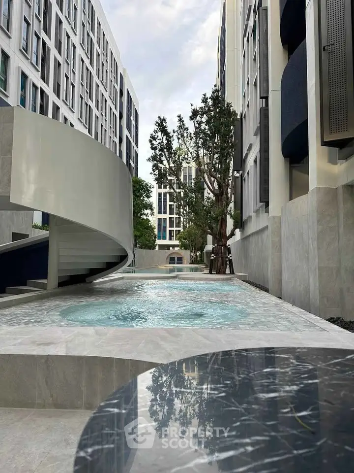 Modern residential building with stylish pool and spiral staircase, offering luxury urban living.