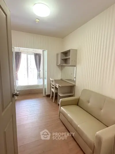 Cozy apartment interior with sofa, desk, and bedroom view