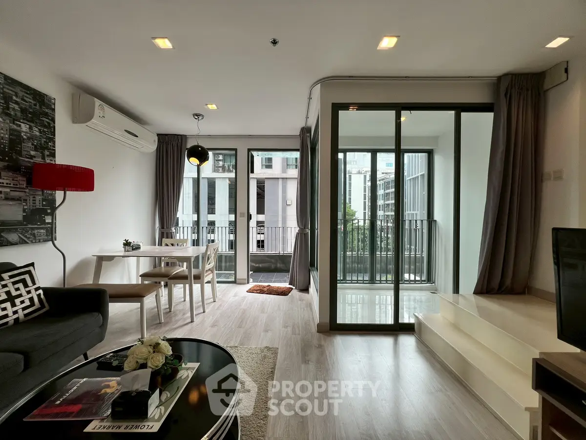 Modern living room with balcony view, stylish decor, and open layout in urban apartment.