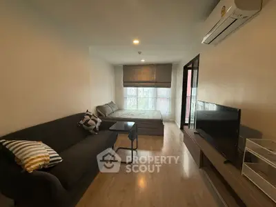 Modern studio apartment with cozy living area and large window view.